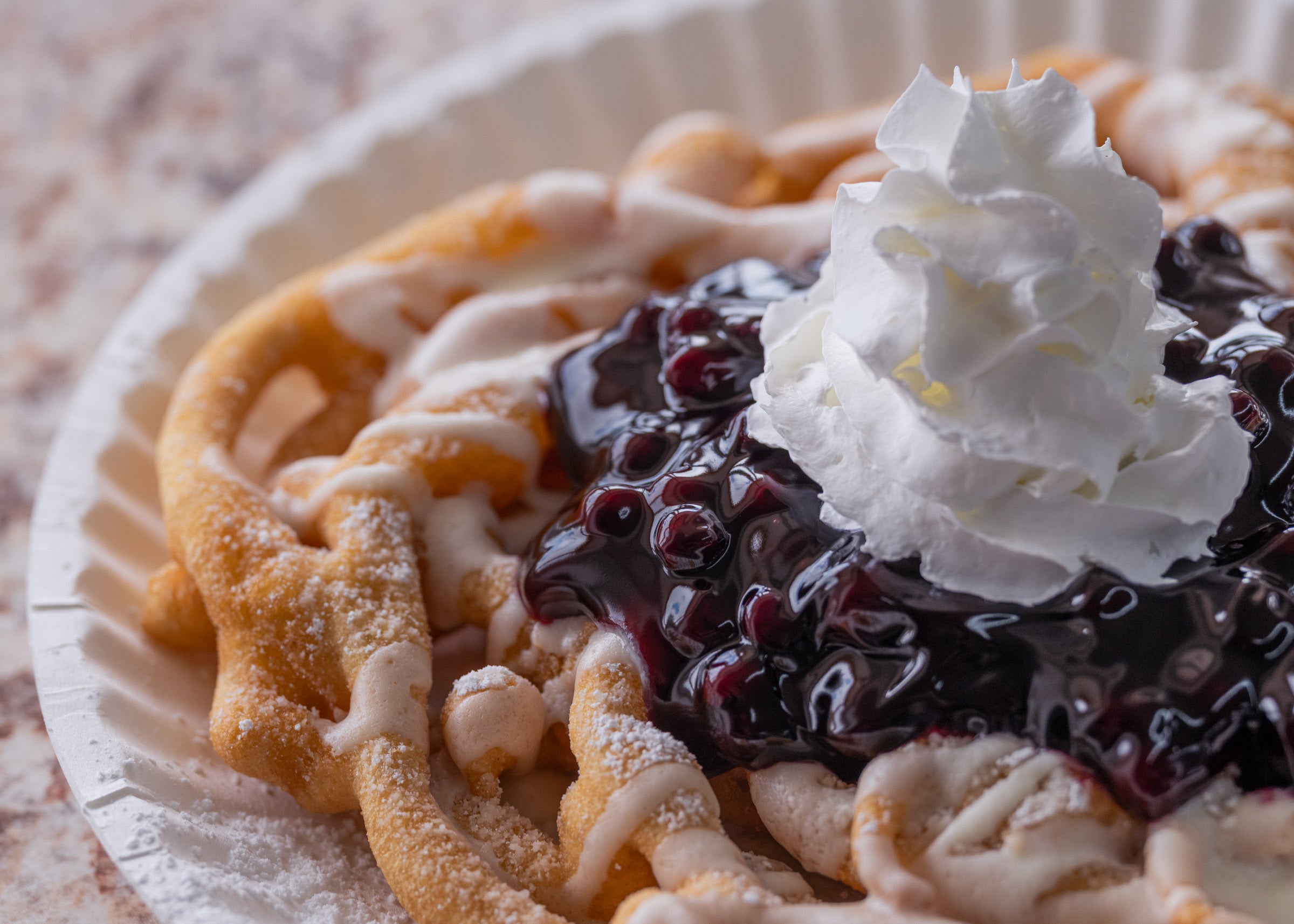 Fried waffle dessert topped with blueberry sauce and whipped cream served on a paper plate at Lakeland Orchard